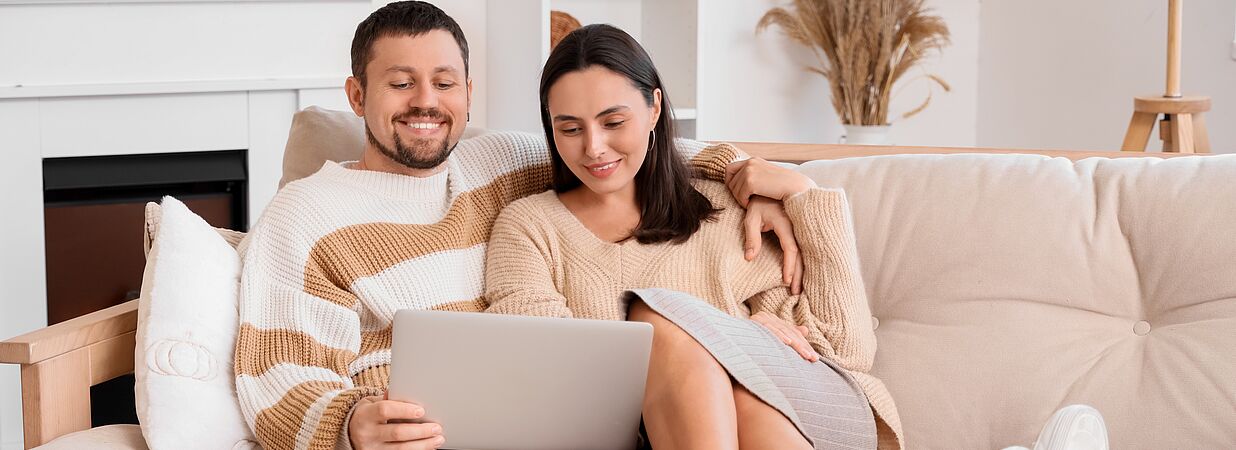 Paar auf Couch in Wohnung mit Laptop