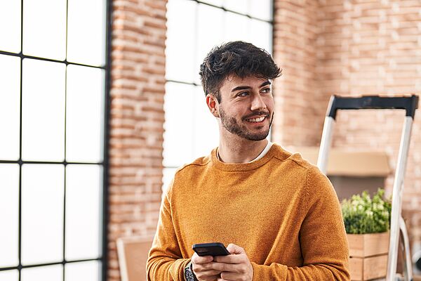 Mann in neuem gemieteten Haus, hält Handy