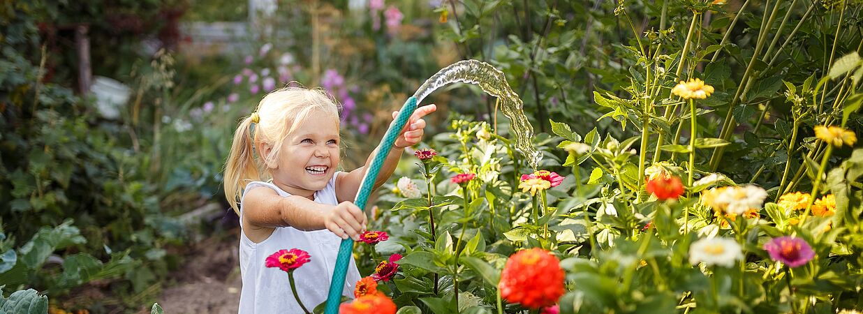 Kind wässert den Garten