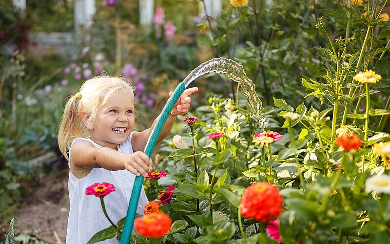 Kind wässert den Garten