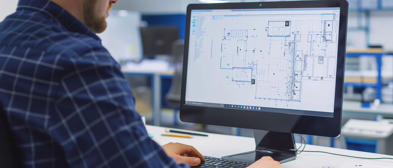 Mann erstellt Grundriss am PC